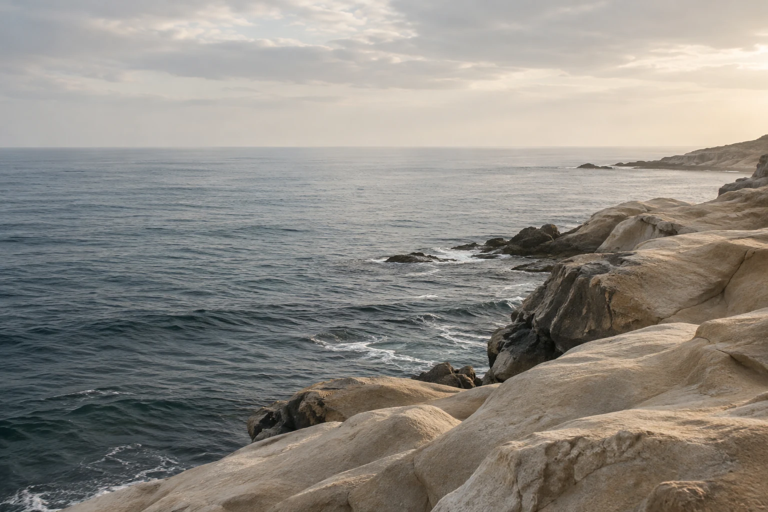 Pale coastal rocks beside a quiet blue-grey sea